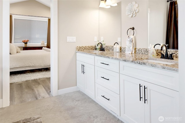 bathroom with a sink, baseboards, ensuite bathroom, and double vanity