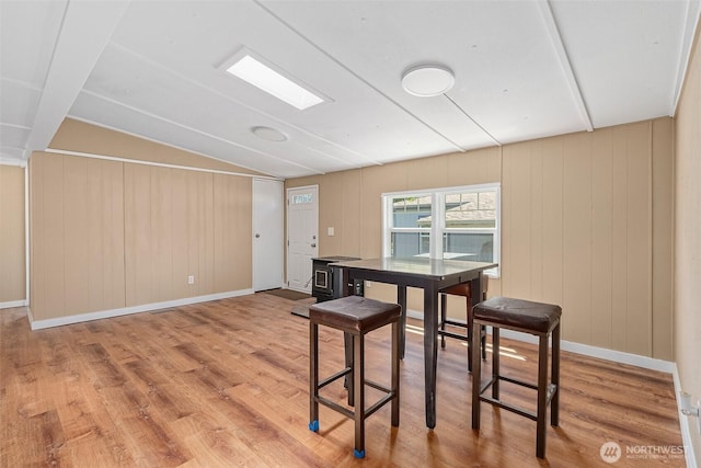 dining area with baseboards, wood finished floors, and vaulted ceiling