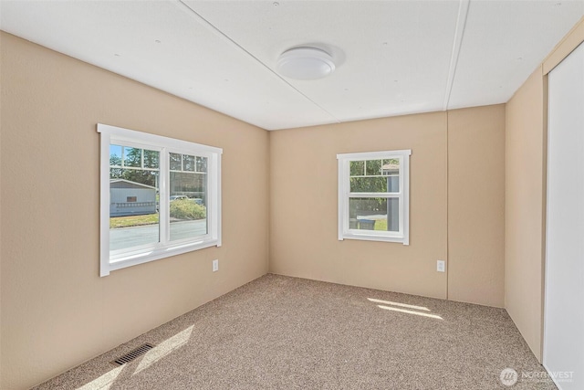 carpeted empty room featuring visible vents