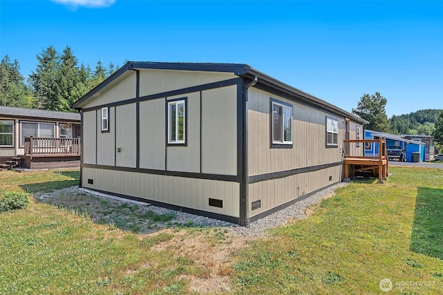 view of side of home with crawl space, a yard, and a deck