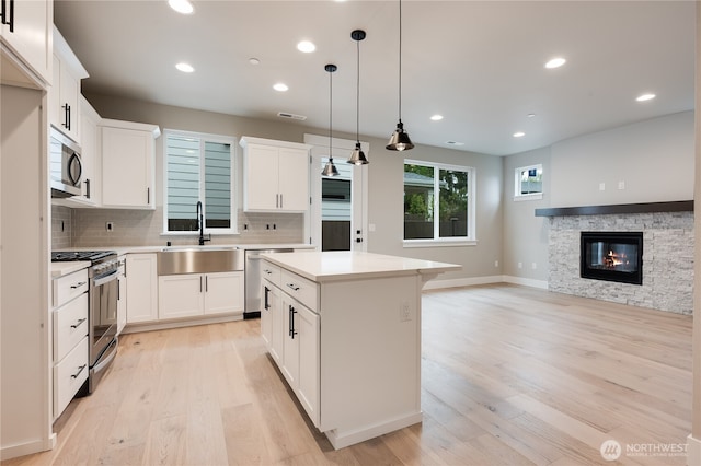 kitchen with visible vents, a sink, backsplash, a center island, and stainless steel appliances