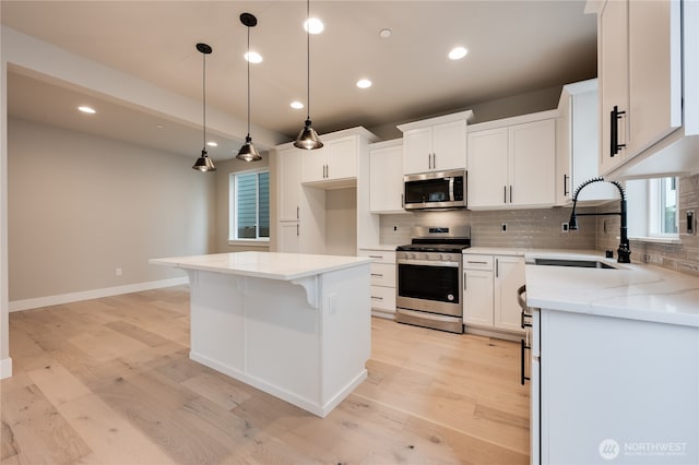 kitchen with tasteful backsplash, appliances with stainless steel finishes, light wood-type flooring, and a sink