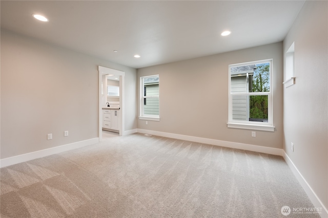 empty room with light carpet, recessed lighting, and baseboards