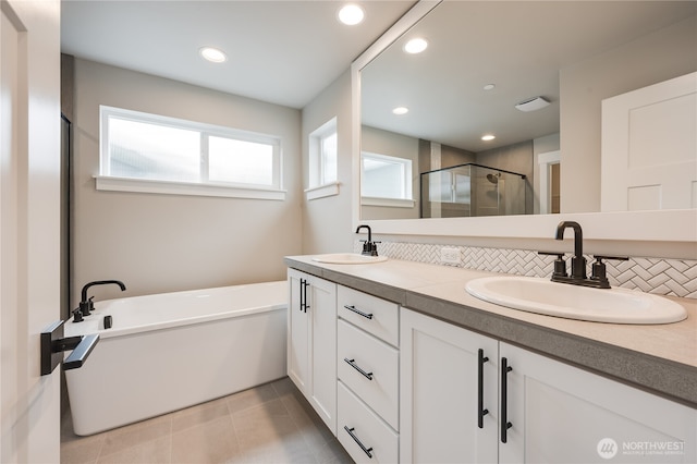 bathroom with tile patterned floors, a shower stall, double vanity, and a sink