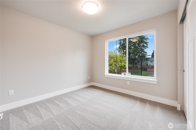 carpeted spare room featuring baseboards