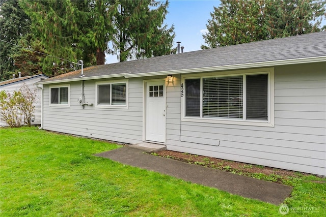 view of front of home with a front lawn and a shingled roof