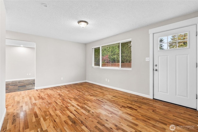 entrance foyer featuring a textured ceiling, baseboards, and wood finished floors