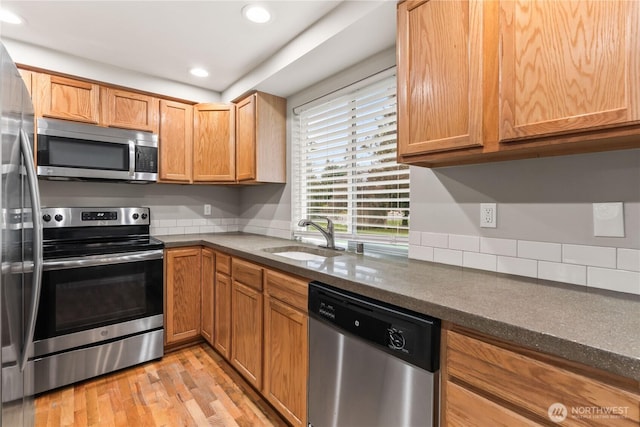 kitchen with a sink, stainless steel appliances, light wood-type flooring, and recessed lighting