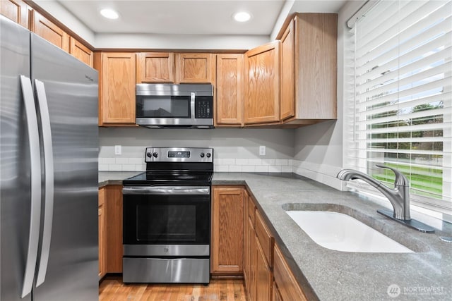 kitchen with a sink, dark countertops, recessed lighting, stainless steel appliances, and light wood finished floors