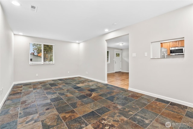 spare room with stone tile floors, recessed lighting, baseboards, and visible vents