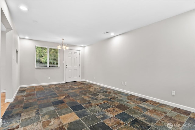 spare room with recessed lighting, stone finish floor, an inviting chandelier, and baseboards