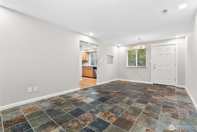 empty room with visible vents, baseboards, stone tile floors, and an inviting chandelier