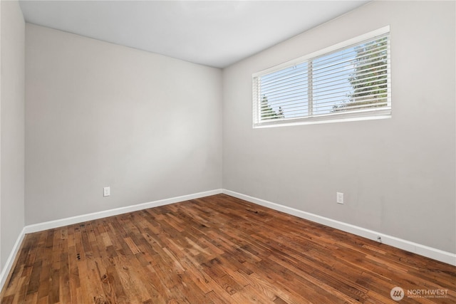 empty room featuring baseboards and wood-type flooring