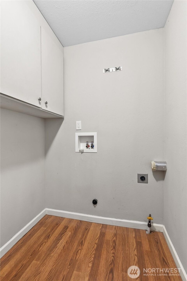 clothes washing area with washer hookup, wood finished floors, cabinet space, hookup for an electric dryer, and gas dryer hookup