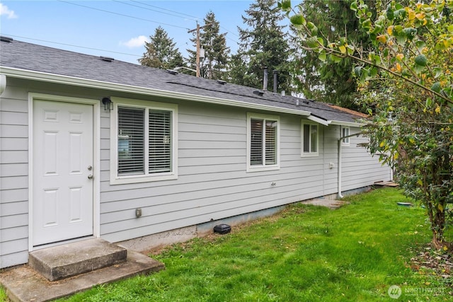 rear view of property with a lawn and roof with shingles