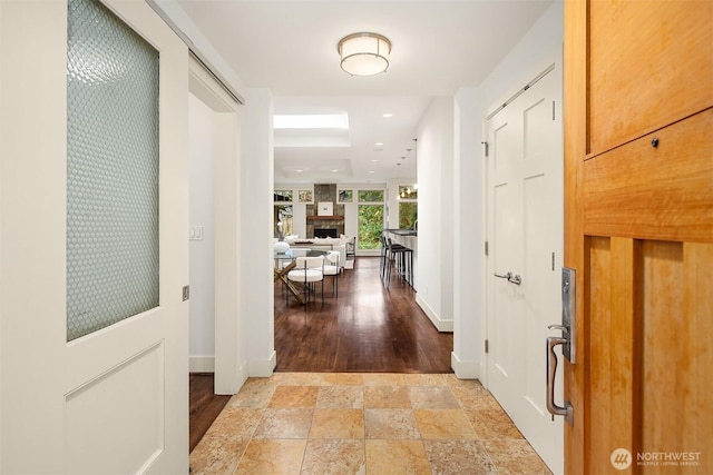 corridor with recessed lighting, stone finish flooring, and baseboards