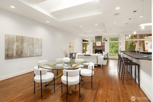 dining area with recessed lighting, a tray ceiling, baseboards, and dark wood finished floors