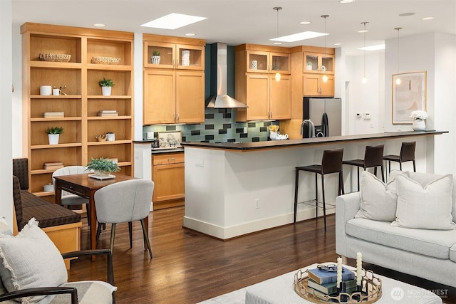 kitchen featuring glass insert cabinets, wall chimney range hood, dark wood-style floors, and stainless steel refrigerator with ice dispenser