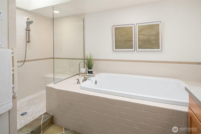 bathroom featuring vanity, a garden tub, and walk in shower