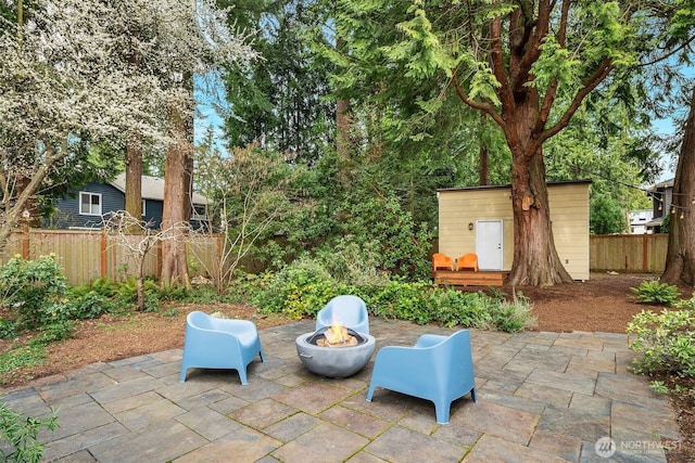 view of patio / terrace featuring an outdoor structure, fence, and an outdoor fire pit