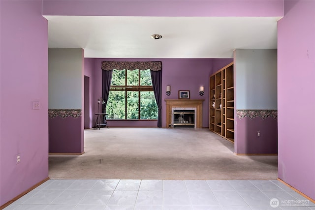 unfurnished living room featuring tile patterned floors, a glass covered fireplace, and carpet