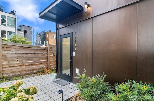 entrance to property featuring stucco siding and fence