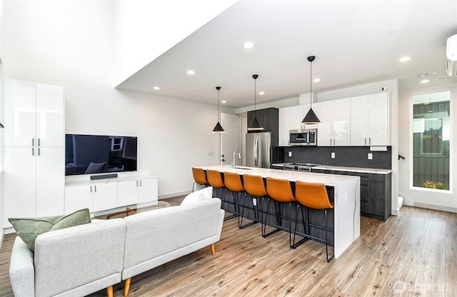 kitchen featuring modern cabinets, a kitchen breakfast bar, appliances with stainless steel finishes, white cabinets, and light countertops