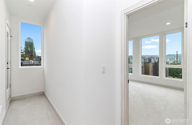 hall with recessed lighting, light colored carpet, and baseboards