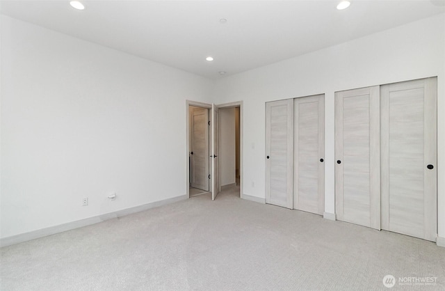 unfurnished bedroom featuring recessed lighting, baseboards, light carpet, and multiple closets