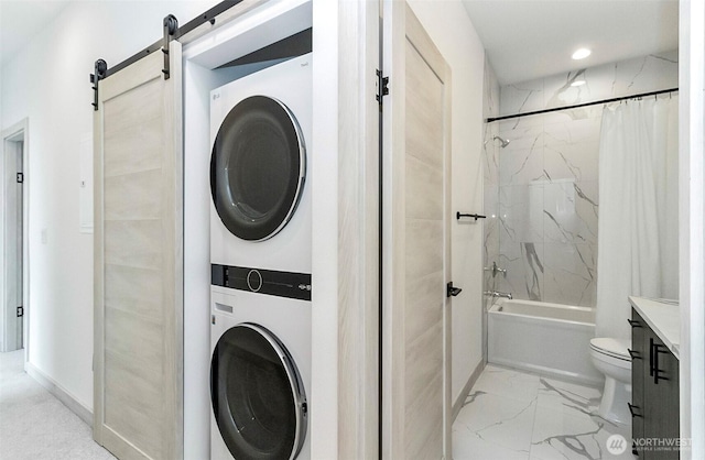 washroom with a barn door, stacked washer / dryer, recessed lighting, and marble finish floor