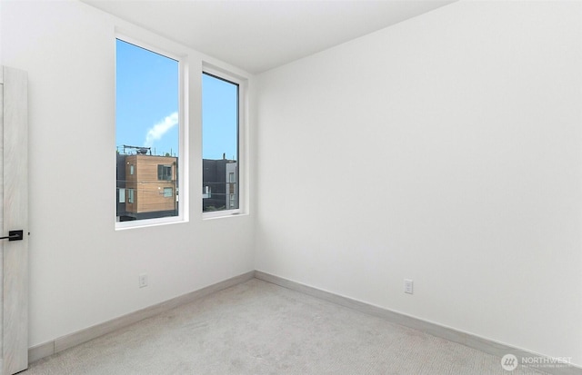 unfurnished room featuring baseboards and light carpet