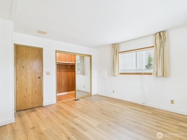 unfurnished bedroom featuring baseboards, visible vents, a closet, and light wood-type flooring