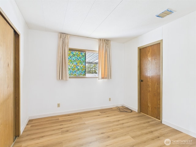 unfurnished bedroom featuring visible vents, baseboards, light wood-style floors, and a closet