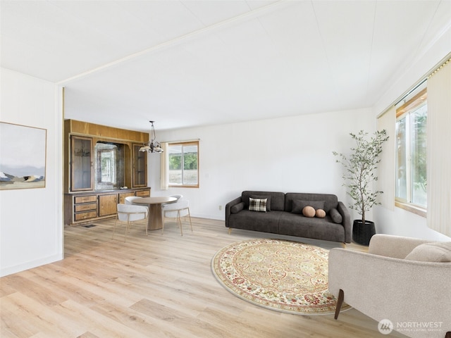 living area with light wood-type flooring and an inviting chandelier