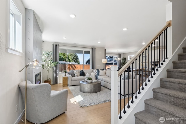 living area with recessed lighting, stairs, and wood finished floors