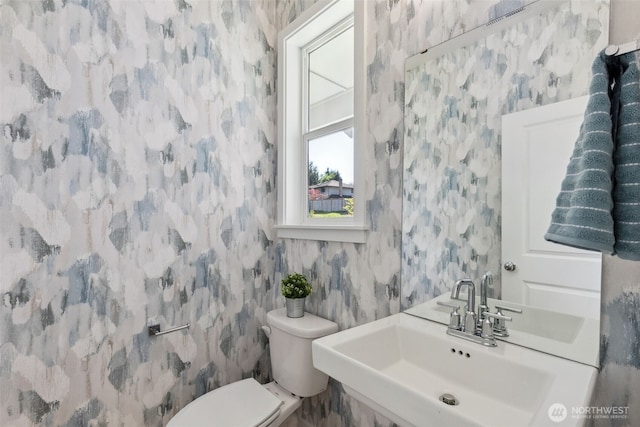 bathroom featuring wallpapered walls, toilet, and a sink