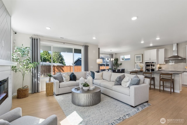 living room featuring recessed lighting, a fireplace, and light wood finished floors