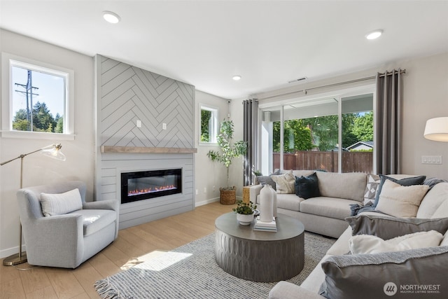 living room featuring recessed lighting, visible vents, a large fireplace, and wood finished floors