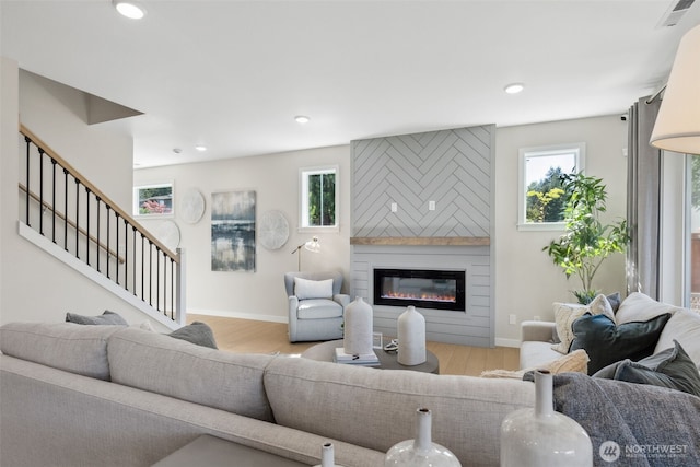 living room featuring wood finished floors, a fireplace, visible vents, and a wealth of natural light