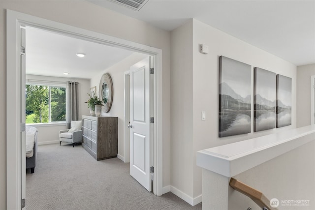 hall with visible vents, baseboards, and carpet