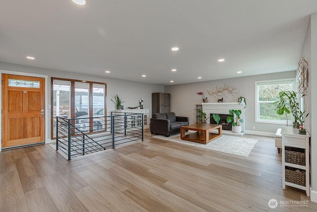 living room featuring recessed lighting, a fireplace with raised hearth, and wood finished floors