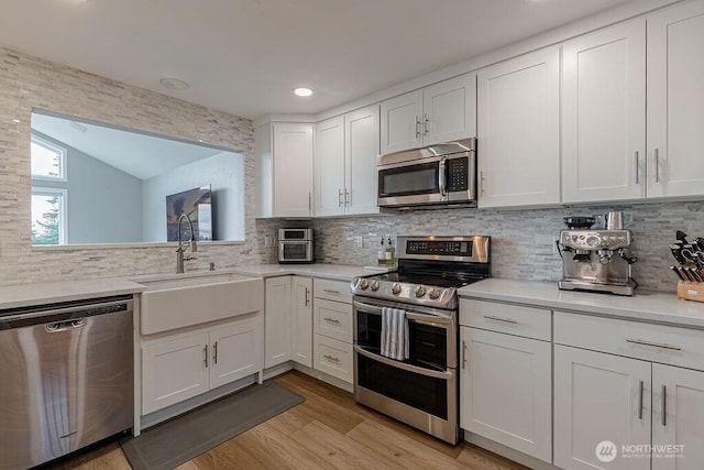 kitchen with a sink, light countertops, white cabinetry, and stainless steel appliances