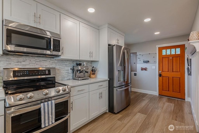 kitchen with tasteful backsplash, light wood-type flooring, light countertops, appliances with stainless steel finishes, and white cabinets