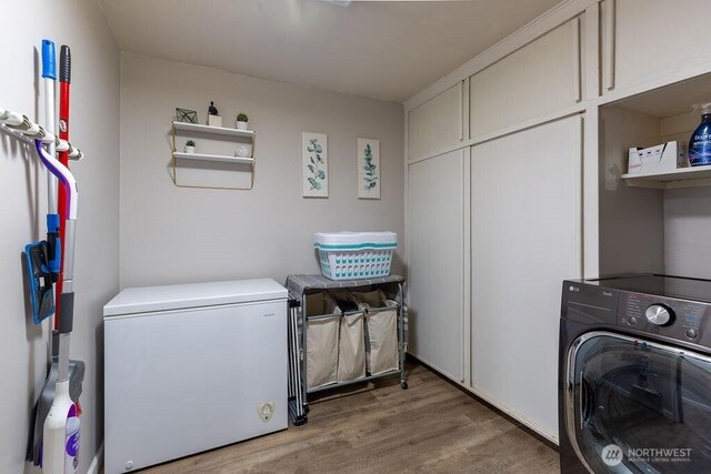 laundry area with cabinet space, washer / clothes dryer, and light wood-style floors