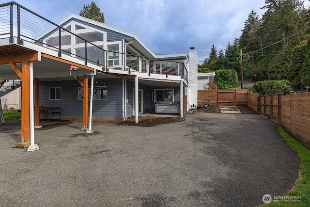 back of house featuring a balcony and fence