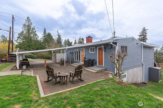 back of house featuring a patio, a lawn, a chimney, and fence