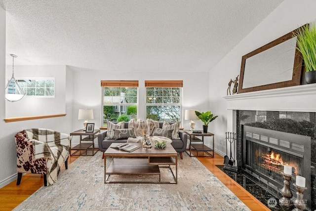 living room with wood finished floors, a fireplace, baseboards, and a textured ceiling