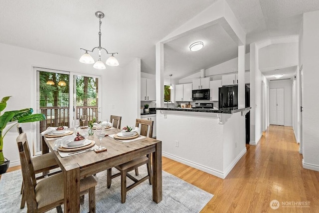 dining room with baseboards, a chandelier, vaulted ceiling, light wood-style flooring, and a textured ceiling