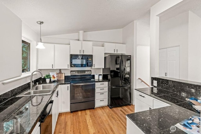 kitchen with light wood finished floors, a sink, black appliances, vaulted ceiling, and white cabinetry