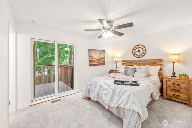 bedroom with a textured ceiling, visible vents, light colored carpet, and access to outside